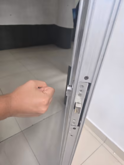 Mano intentando deslizar la misma puerta corrediza por el riel, sin ninguna manija de la que sujetarse.
