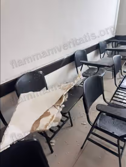 Trozo de aplanado de techo, partido y con escombro, caído sobre el respaldo y el paletero de una banca del aula 2301, con fragmentos de material dispersos en el piso y sobre otras bancas cercanas.