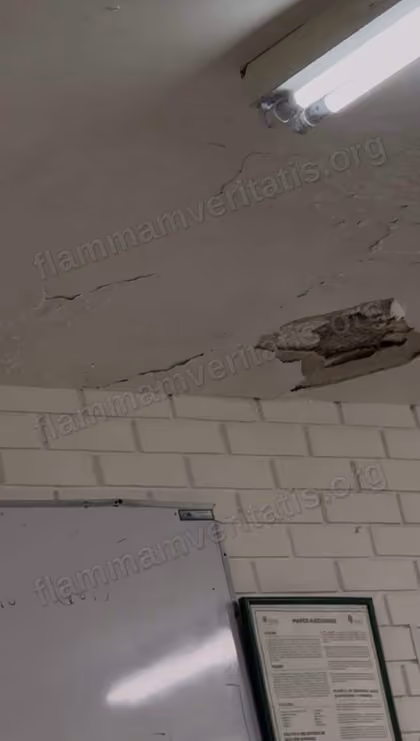 Techo del aula 3301 con una grieta grande y un trozo de aplanado desprendido junto a una lámpara, sobre un pizarrón y un cartel de la Facultad.
