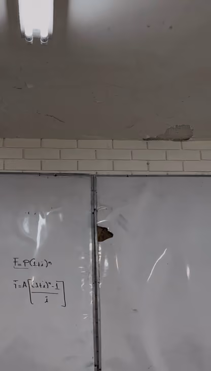 Techo del aula 3301 con grietas y un trozo de aplanado caído sobre el borde de ladrillo, encima de un pizarrón con una zona inflada y perforada.