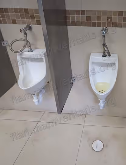 Dos mingitorios en un baño con divisiones metálicas; el de la derecha tiene orina acumulada sin vaciar en el fondo.